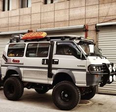 a white truck parked in front of a building with a pizza on top of it