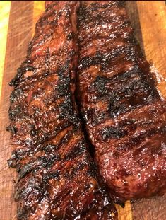 two pieces of meat sitting on top of a wooden cutting board