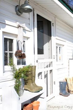 a white house with boots and plants on the porch