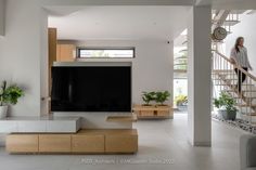 a woman walking up the stairs in front of a flat screen tv on a stand