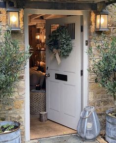 a white door with a wreath on it and two buckets full of plants next to it