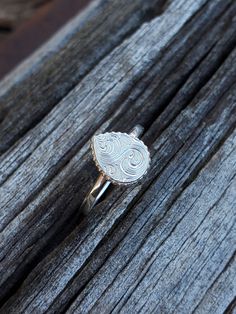 a silver ring sitting on top of a wooden table next to a piece of wood