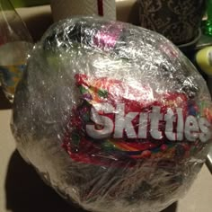 a plastic wrapper wrapped around a skittle's candy ball on a counter