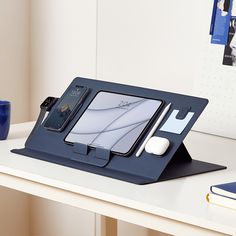 an ipad and headphones are sitting on a desk with a blue tablet case in front of it