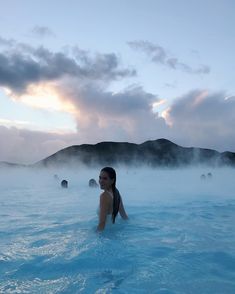 a woman sitting in the middle of a body of water with steam rising from it