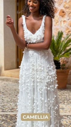 a woman wearing a white dress with flowers on it and the words camellia written in gold