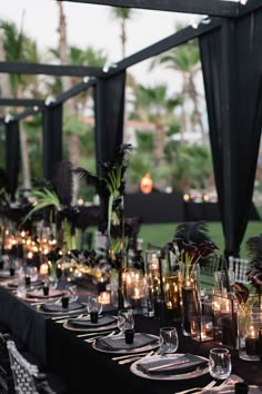 a long table is set with candles and black linens for an elegant dinner party