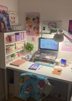 a laptop computer sitting on top of a white desk next to a shelf filled with books