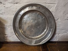 a metal plate sitting on top of a wooden table next to a white brick wall