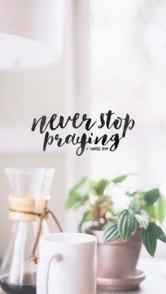 a coffee mug sitting on top of a table next to a potted plant with the words never stop praying