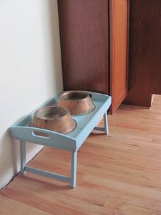 two pots are sitting on a blue tray in front of a wooden door and wall