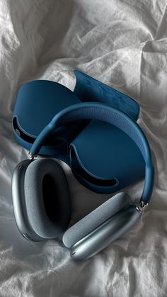 a pair of blue headphones laying on top of a white sheet with a matching case