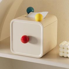 a white box sitting on top of a shelf next to some balls and a red ball