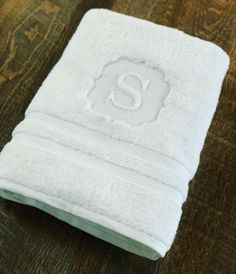 a white towel with the letter s on it sitting on top of a wooden table