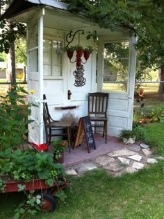 a small white shed with a table and chairs on the front porch next to it