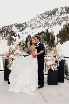 a bride and groom kissing in front of the mountains