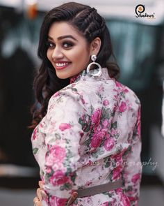 a woman in a floral dress with large hoop earrings