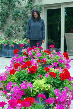 a woman standing next to a large pot full of flowers