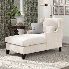 a white chair sitting on top of a rug in front of a window with curtains