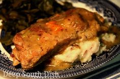 a blue and white plate topped with meat covered in gravy next to greens