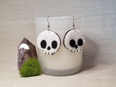 a pair of skull earrings sitting next to a rock