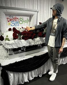 a man standing in front of a table with flowers on it and a sign behind him