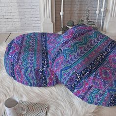 a blue and pink blanket sitting on top of a white rug next to a cup