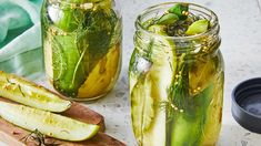 two jars filled with pickles sitting on top of a counter