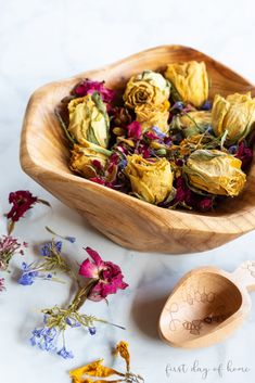 dried flowers in a wooden bowl next to a spoon