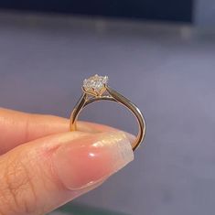 a close up of a person's hand holding a ring with a diamond on it