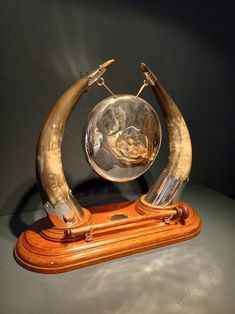 an antique clock with two horns on it's sides and a glass bowl in the middle