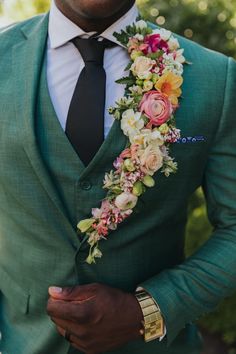 a man in a green suit with flowers on his lapel