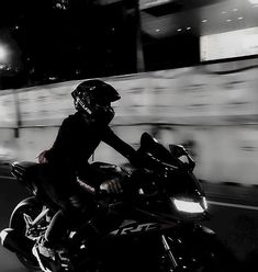 a man riding on the back of a motorcycle down a street at night with motion blur