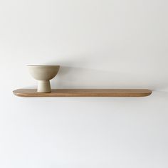 a wooden shelf with a white bowl on it