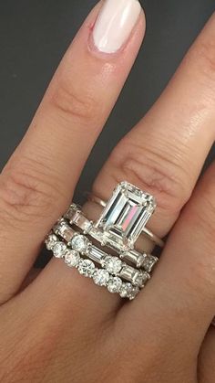 a close up of a person's hand with two rings on their fingers and an engagement ring