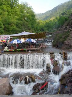 there is a waterfall that has many tables and umbrellas on it in the water