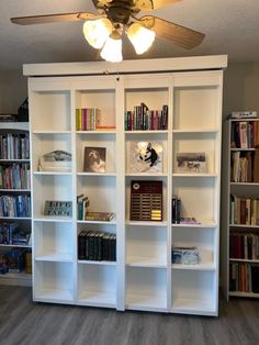 a room filled with lots of books and a ceiling fan