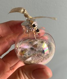 a hand holding a glass ornament filled with sand