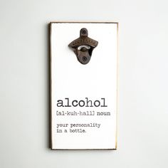 a bottle opener with the words alcohol on it hanging from a white wall next to a sign that says alcohol