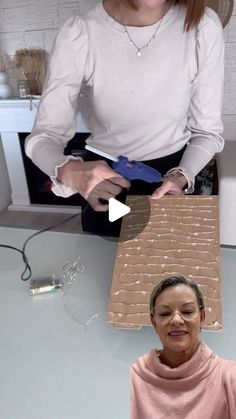 a woman standing in front of a cardboard box on top of another woman's head