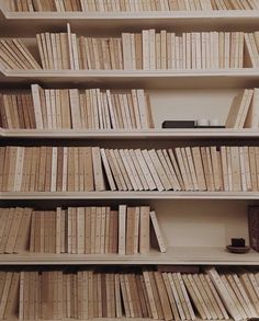 a bookshelf filled with lots of books on top of wooden shelves