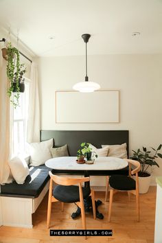 a living area with a couch, table and plants on the windowsill in front of a window sill