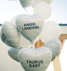 several white heart shaped balloons with the words angel landing and taurus baby written on them