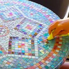 a person using a sponge to clean a mosaic table