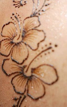 the back of a woman's shoulder with flowers drawn on it and glitters