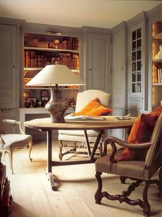 a living room filled with furniture and a lamp on top of a wooden table in front of bookshelves