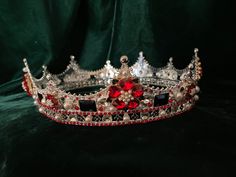 This  full circle crown is stunning.  Embellished with rhinestone Tudor roses (see my other listing for the roses as buttons) I had the specially made.   This crown would be ideal for a Tudor queen, or the queen of your heart. Each rose is made up of 5 heart shaped red petals.  Red, black and clear rhinestones adorn this crown as well as acrylic pearls.  The crown is  2.25 inches tall.  The inside circumference is approximately  23.75 inches.  Diameter is 7.5 inches.  Padding may be added to make crown smaller.  I sned it shaped into an oval.  You may gently push in on the sides to custom fit the shape of your head if needed.  It is made of metal zinc alloy embellished with rhinestones and faux pearls.  Need something with a smaller circumference?  Please look at my six pointed crown.  Thi Elegant Red Ceremonial Headpieces, Elegant Tall Crown With Rhinestones, Silver Rhinestone Crown Headpiece, Elegant Silver Crown With Rhinestones, Regal Tall Crown For Formal Occasions, Formal Tall Regal Crown, Red Crown Jewelry For Wedding, Royal Tall Crown For Wedding, Elegant Rhinestone Crown Jewelry