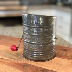 an old metal container with a cherry on the side sitting on a wooden table top