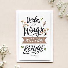 a card with the words under his wings you will find refuge on it next to some flowers