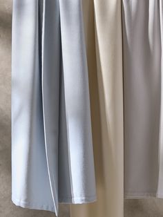 three different colored pants hanging up on a clothes line, one in white and the other in light blue